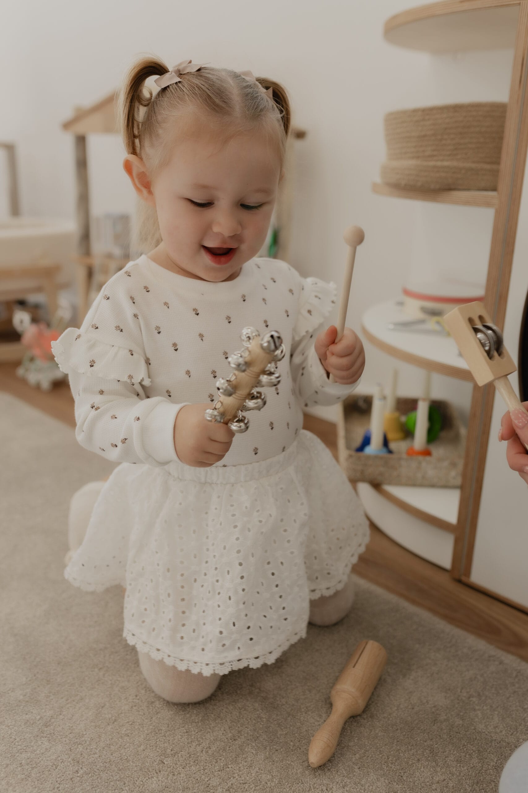 A toddler girl playing with wooden musical shaker instruments