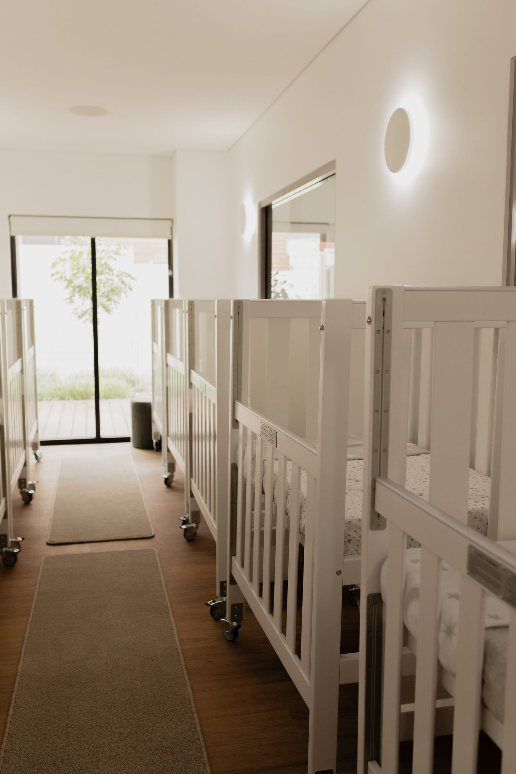 A row of baby cots lined up in the nursery sleep room
