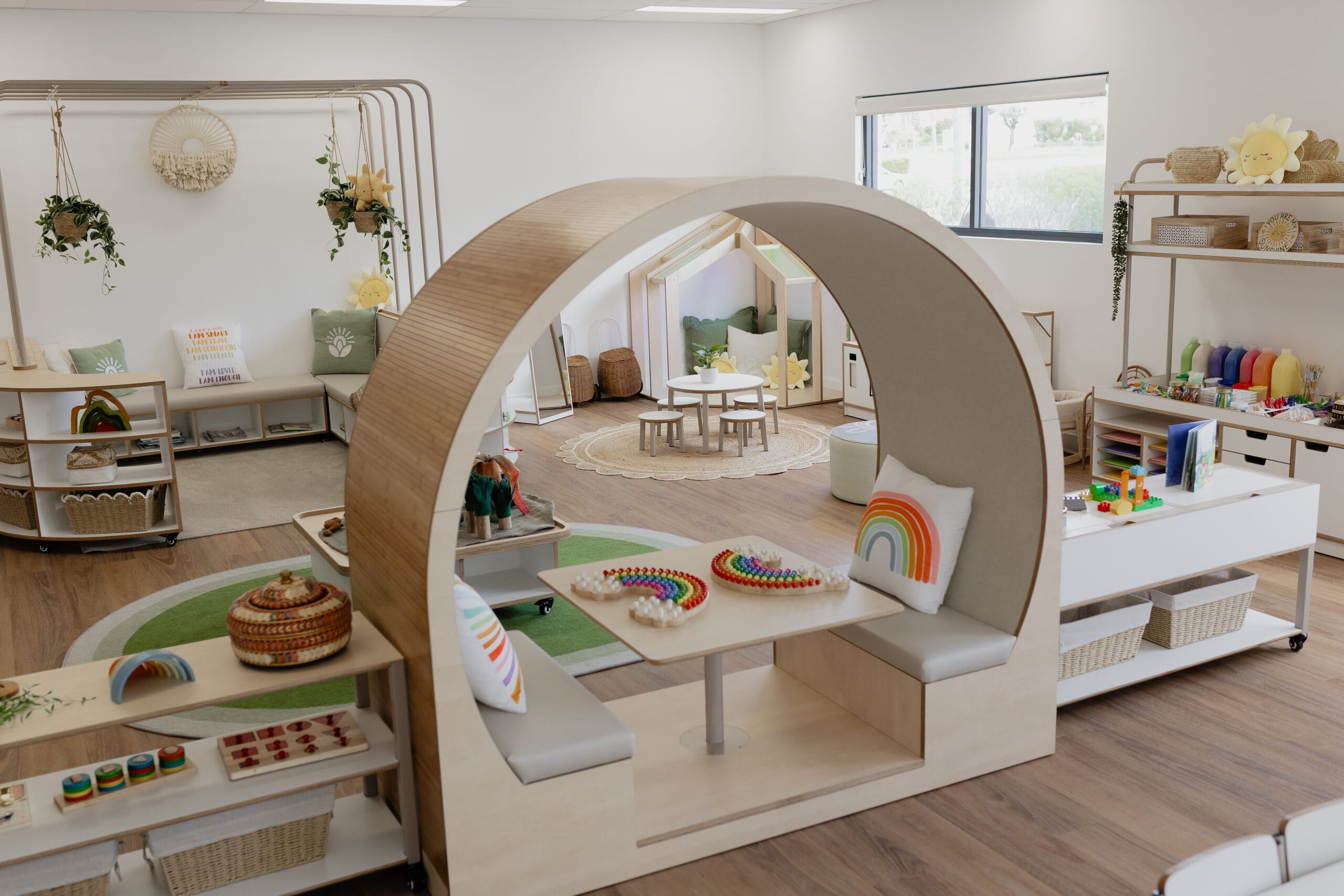 The empty Sun Room featuring a cozy arched reading nook, shelving with toys, and a play table