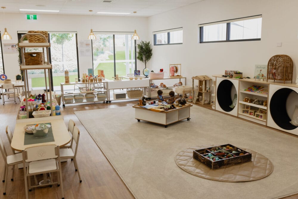 The empty Universe Room featuring play tunnels, shelving with toys, and a table with chairs