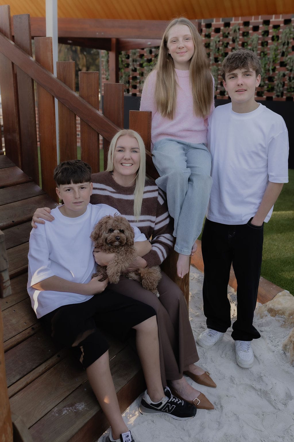 A family with three children and a small dog sitting together on outdoor steps