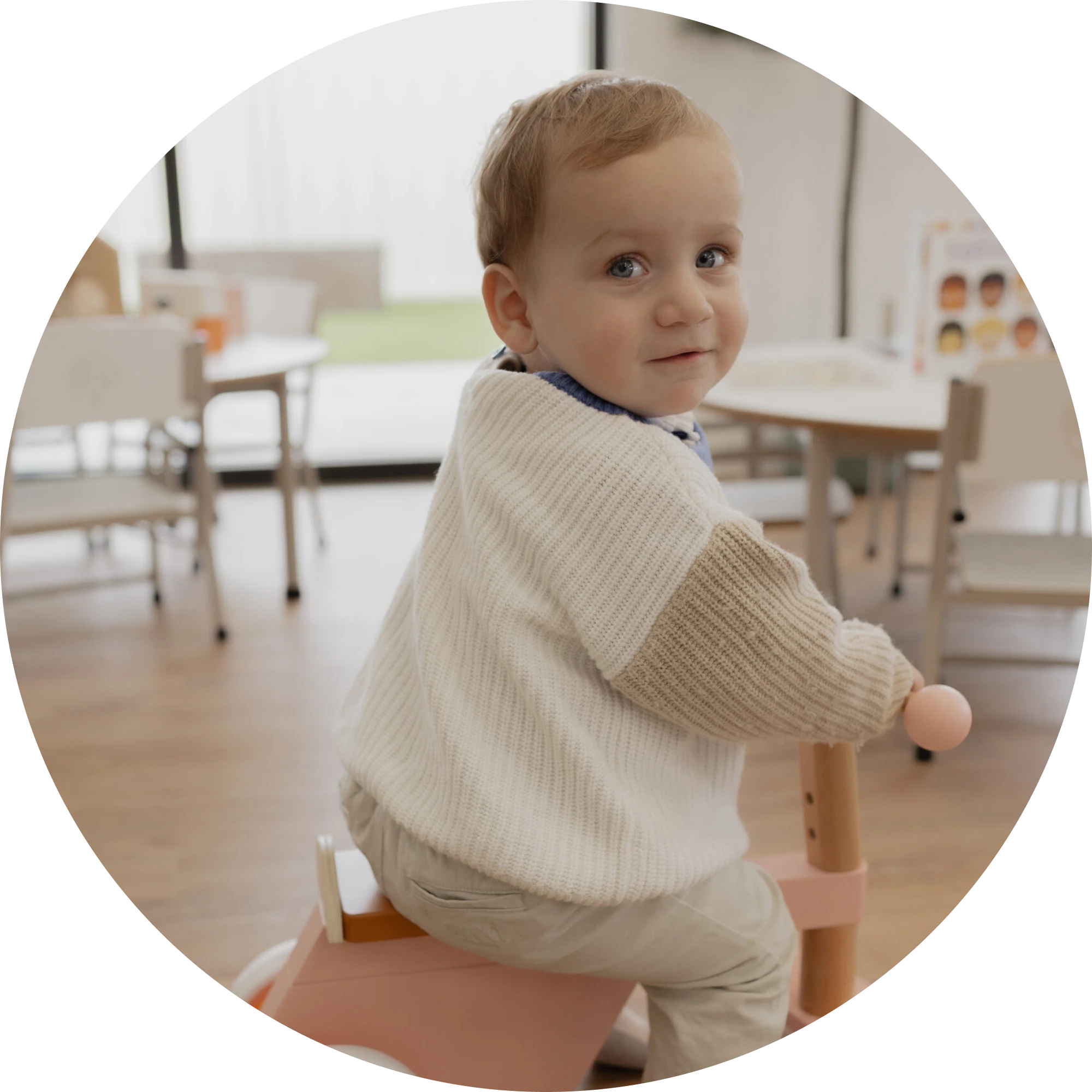 A toddler riding a wooden rocking toy indoors