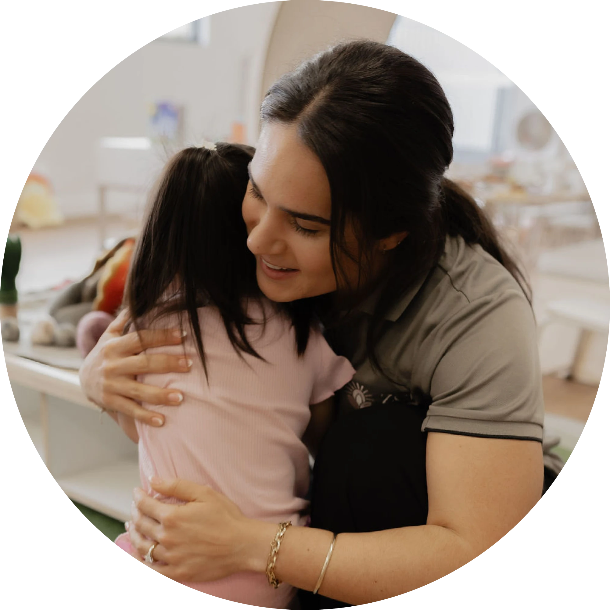 An educator giving a warm hug to a child in the playroom