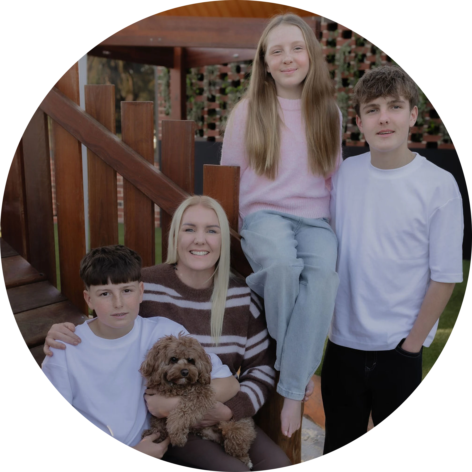 A family with three children and a small dog sitting together on outdoor steps