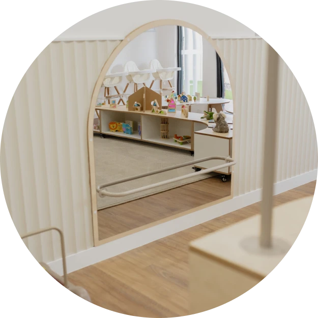 View through an arched doorway into the Stars Room with a shelf of toys and high chairs